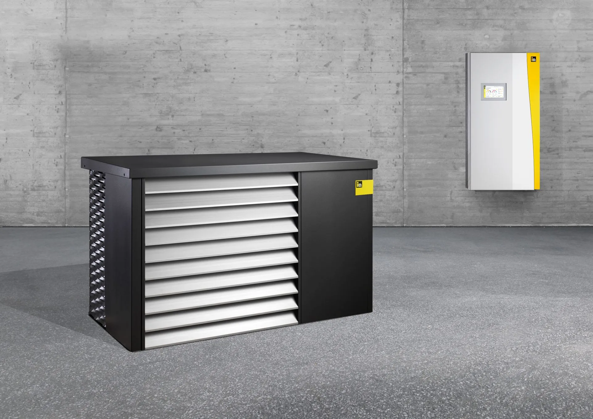 Innen- und Außeneinheit der Wärmepumpe iDM AERO ALM 2-8 und 4-12 in einem leeren, grauen Raum.