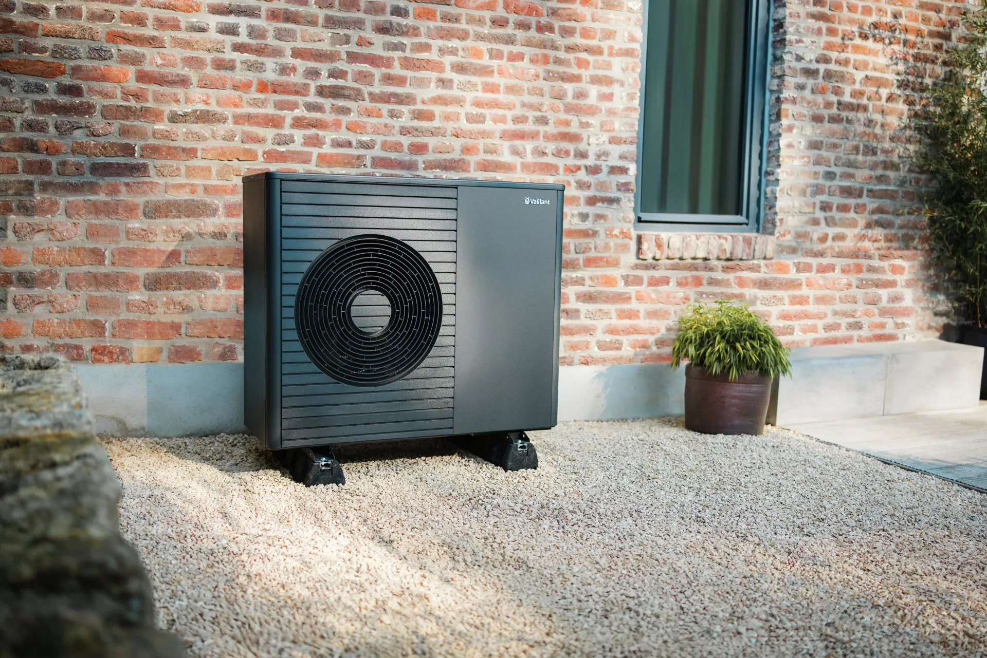 Eine moderne Vaillant-Wärmepumpe steht vor einem Backstein-Altbau.