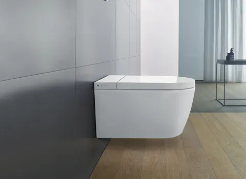 Wandhängendes Duravit Dusch-WC in einem minimalistischen Badezimmer mit dunklen Wandfliesen und hellem Holzboden.