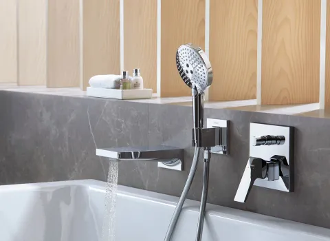 Eine moderne Badewanne mit einem eleganten, rechteckigen Wasserhahn, aus dem Wasser fließt.