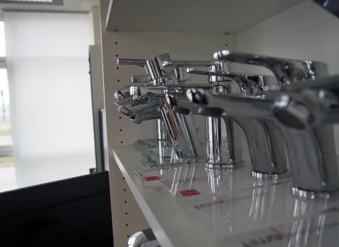 Eine Reihe glänzender Chrom-Wasserhähne ist in einem Regal auf mehreren Ebenen ausgestellt.