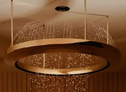 Nahaufnahme einer modernen, goldenen Regendusche, aus der gleichmäßige Wasserstrahlen sanft herabrieseln.