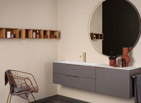 Stocco Badmöbel in Taupe mit rundem Spiegel, goldener Armatur und offenen Wandregalen aus Holz.